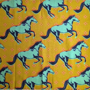 Puede incluir: Tela de color amarillo mostaza con un patrón repetido de caballos corriendo en verde azulado y azul marino. Los caballos tienen un contorno rojo y están sobre un fondo de pequeñas formas florales rosas. La tela tiene una estética vintage.