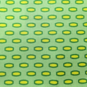May include: A green fabric with a repeating pattern of yellow ovals with green outlines.
