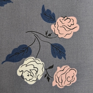 Puede incluir: Primer plano de una tela gris con un estampado floral. El diseño presenta rosas rosas y blancas, hojas azul oscuro y tallos negros. Las rosas están estilizadas con contornos delicados, creando una estética vintage.