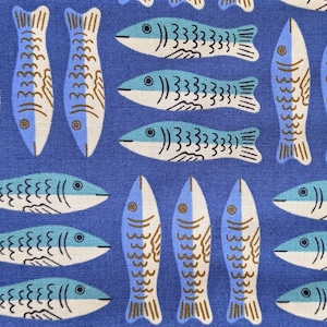 Può includere: Primo piano di un tessuto blu con un motivo ripetuto di pesci stilizzati. I pesci sono bianchi, azzurri e marroni. Il motivo è disposto in file e colonne, creando un design giocoso e nautico.