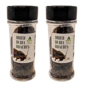 May include: Two clear plastic jars with black lids, each labeled "Dried Dubia Roaches." The labels also include the text "ezbotanicals" and "2 oz (56 grams)." The jars are filled with dried insects.