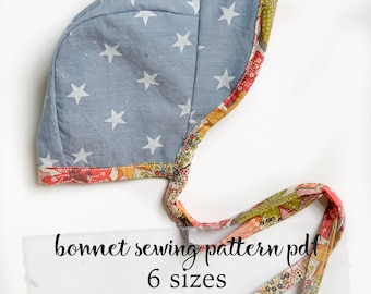 May include: A blue bonnet sewing pattern with white stars printed on the fabric. The bonnet is trimmed with a floral fabric. The text on the image reads "bonnet sewing pattern pdf 6 sizes brimmed or brimless".