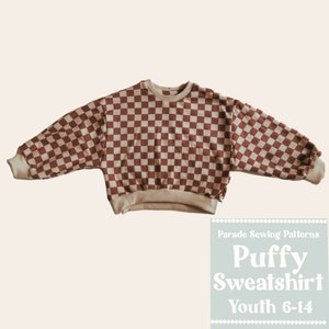 May include: A red and beige checkered puffy sweatshirt for youth sizes 6-14. The sweatshirt has a relaxed fit and long sleeves.  Parade Sewing Patterns.