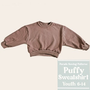May include: A mauve-colored puffy sweatshirt sewing pattern for youth sizes 6-14. The pattern is from Parade Sewing Patterns.