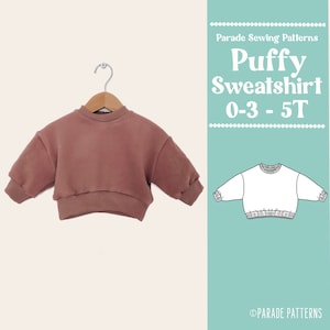 May include: A brown puffy sweatshirt for babies and toddlers, sizes 0-3 to 5T. The sweatshirt is on a hanger and has a relaxed fit. The text "Parade Sewing Patterns" and "Puffy Sweatshirt 0-3 - 5T" is visible in the image.