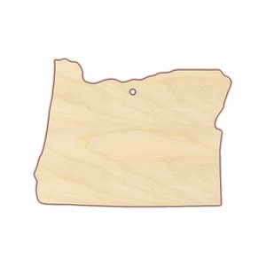 May include: A wooden cutout of the state of Oregon. The cutout is light brown and has a hole in the top for hanging.