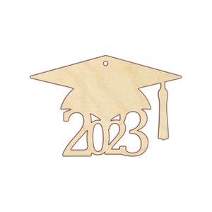 Puede incluir: Adorno de gorro de graduaci&oacute;n de madera con el a&ntilde;o 2023 recortado. El adorno est&aacute; sin terminar y listo para ser pintado o te&ntilde;ido.