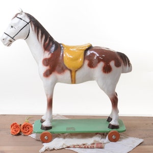 Caballo vintage de juguete de cartón sobre ruedas