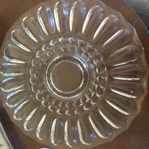 May include: A clear glass serving bowl with a scalloped edge and a raised, diamond-shaped pattern in the center. The bowl has a decorative, scalloped edge.