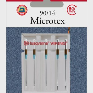 Puede incluir: Paquete de agujas para máquina de coser Husqvarna Viking Microtex, tamaño 90/14. Las agujas son plateadas con detalles en marrón y azul. El paquete tiene los logotipos de Husqvarna y Viking y el texto "FIVE NEEDLES".