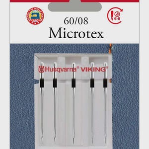 Puede incluir: Paquete de agujas para máquina de coser Husqvarna Viking Microtex. El paquete rojo y blanco muestra los logotipos de Husqvarna y Viking. Contiene cinco agujas, cada una con un vástago plateado y una parte superior negra. El texto "60/08" está impreso en el paquete.