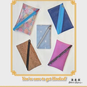 May include: An assortment of The Angler bags in various colors and patterns. The bags include a floral print, blue mesh, light blue with white chevron, cork, and pink. Each bag has a zipper closure. Text on the image reads "The Angler" and "You're sure to get Hooked!"