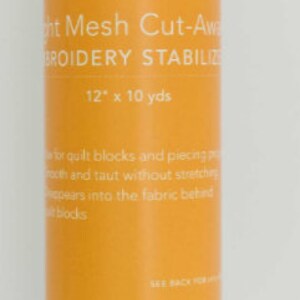 May include: A white roll of light mesh cut-away embroidery stabilizer from the brand "Amberbell". The label says "Light Mesh Cut-Away Embroidery Stabilizer 12" x 10 yds".