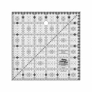 Peut inclure: Une règle de couture en plastique transparent avec une grille noire et une ligne diagonale. La règle est étiquetée "Itty Bitty Eights Square" et "Creative Grids".