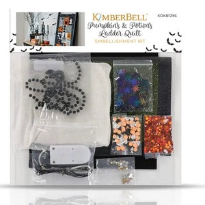 May include: Kimberbell Pumpkin & Potions Ladder Quilt Embellishment Kit. The kit includes a variety of embellishments, including black beads, sequins, and glitter. The kit also includes a white fabric piece, a black fabric piece, and a clear plastic bag.