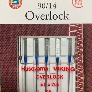 Może przedstawiać: Opakowanie igieł do maszyny do szycia Husqvarna Viking Overlock. Opakowanie jest czerwono-białe, z napisem "90/14 Overlock" i "EL x 705 90". Igły są srebrne z niebieskimi akcentami.