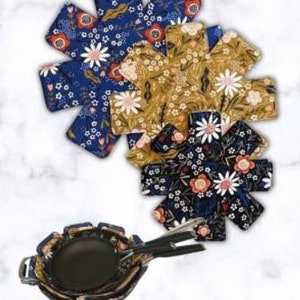 Può includere: Tre proteggi-padelle con motivo floreale in blu, giallo e nero con accenti bianchi. I proteggi-padelle hanno la forma di una stella a otto punte. L'immagine mostra anche tre padelle nere con i proteggi-padelle sopra. Il testo "Pan Protectors" è in alto nell'immagine.