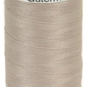 May include: A spool of light taupe sewing thread by Gütermann. The white plastic top label displays Col. 506, a barcode, and the brand name. The white plastic base is printed with 500 m - 547 yds, indicating the length of the thread on the spool.