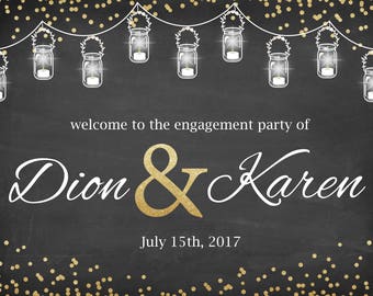 May include: A chalkboard sign with gold glitter accents and white text announcing an engagement party for Dion & Karen on July 15th, 2017. The sign features a string of mason jar lights.
