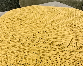 May include: A yellow crocheted blanket with a geometric pattern. The blanket is made with a soft yarn and has a delicate, lacy look.