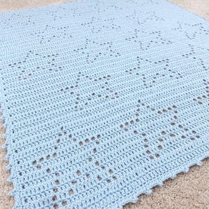 Peut inclure: Une couverture crochetée bleu clair avec un motif d'étoiles répétées. La couverture est faite de fil doux et a un bord festonné. La couverture est idéale pour un bébé ou un enfant.