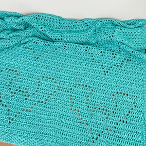 a blue crocheted blanket on a wooden desk