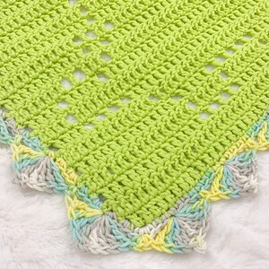 a crocheted blanket is laying on a white blanket