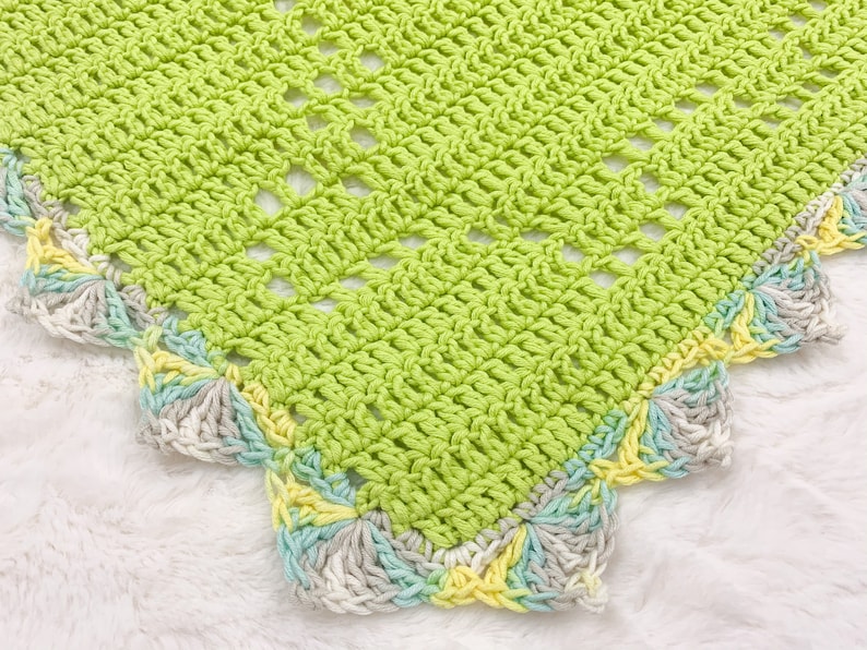 a crocheted blanket is laying on a white blanket