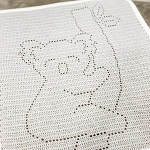 May include: White crocheted blanket with a black outline of a face.