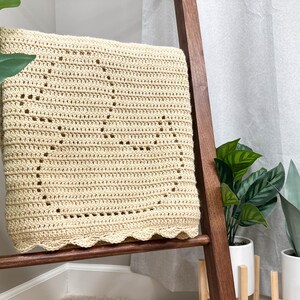 Handmade filet crochet baby blanket, with a rubber duck design and scallop border. Blanket is folded to view a single duck and draped over a wooden blanket ladder.