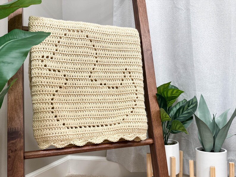 Handmade filet crochet baby blanket, with a rubber duck design and scallop border. Blanket is folded to view a single duck and draped over a wooden blanket ladder.