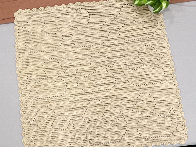Handmade filet crochet baby blanket, with rubber ducky designs. Blanket is made in butter yellow color yarn and laid out on a king sized bed. Perfect gift for newborns or new parents.