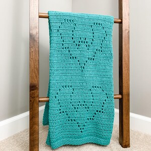 a blue crocheted blanket sitting on top of a wooden ladder