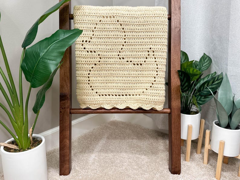 Handmade filet crochet baby blanket, with a rubber duck design and scallop border. Blanket is folded to view a single duck and draped over a wooden blanket ladder.