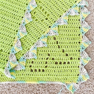 a green crocheted blanket laying on top of a carpet