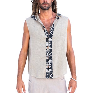 Op de afbeelding: Een mouwloos hooded shirt met een zwart-wit geometrisch patroon op de voorkant. Het shirt is gemaakt van een licht beige stof en heeft een knoopsluiting.