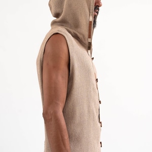 May include: A sleeveless hooded vest with a brown and white trim. The vest is made of a textured fabric and has a button closure.
