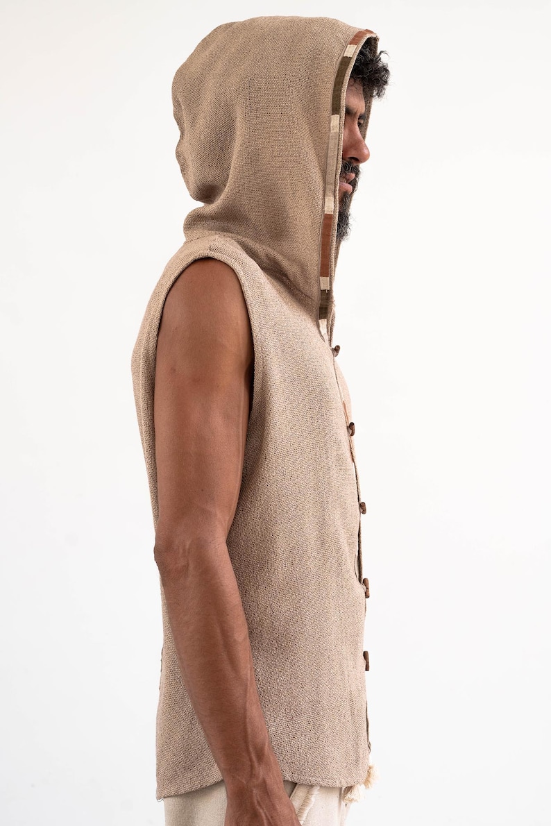 May include: A sleeveless hooded vest with a brown and white trim. The vest is made of a textured fabric and has a button closure.