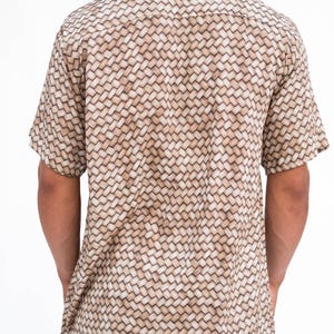 May include: Short-sleeved button-down shirt with a woven basket pattern in shades of tan and cream. The shirt has a classic collar and is made of a lightweight fabric, suitable for warm weather.