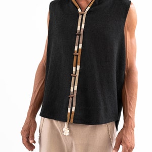 May include: A sleeveless black hooded top with a brown and white trim down the front. The top has a button closure and a relaxed fit.