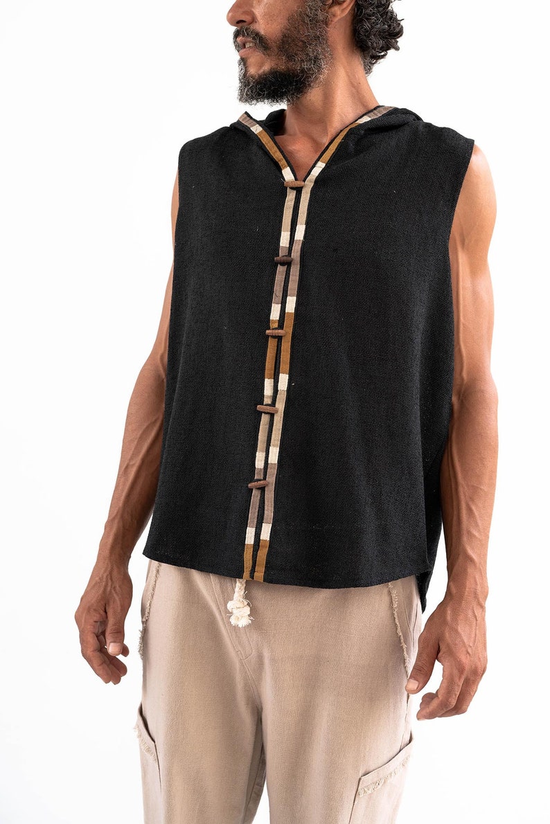 May include: A sleeveless black hooded top with a brown and white trim down the front. The top has a button closure and a relaxed fit.