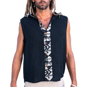 Op de afbeelding: Een mouwloos hooded shirt met een zwarte gebreide stof en een wit en zwart geometrisch patroon aan de voorkant. Het shirt heeft houten knopen.