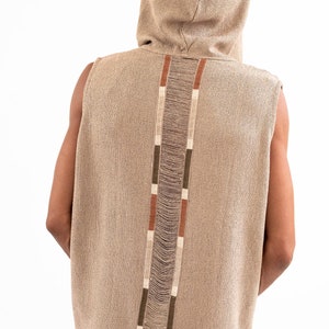 May include: A sleeveless hooded top with a brown, beige, and white striped design down the back. The top is made of a textured fabric.
