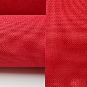 May include: A roll of red fabric with a woven texture. The fabric is rolled up and the end is lying flat.
