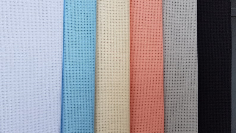 May include: A close-up of seven fabric swatches in different colors. The swatches are arranged horizontally from left to right: white, light blue, cream, peach, light gray, black.