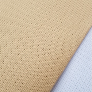 May include: Two pieces of Aida cloth, one beige and one white, showing the weave of the fabric.