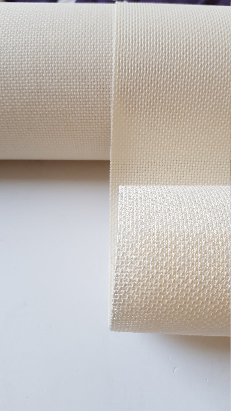 May include: A roll of white Aida cloth, a type of fabric used for cross-stitch embroidery.