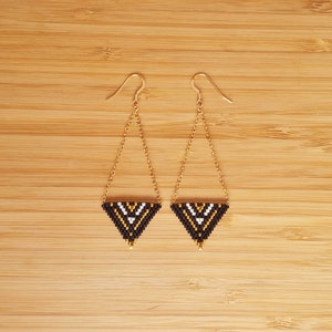 May include: A pair of gold chain earrings with black, white, and gold triangle-shaped beaded pendants.