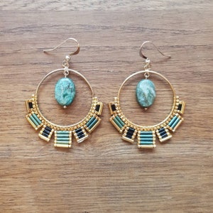 May include: A pair of gold hoop earrings with green stone accents and black and green bead detailing.