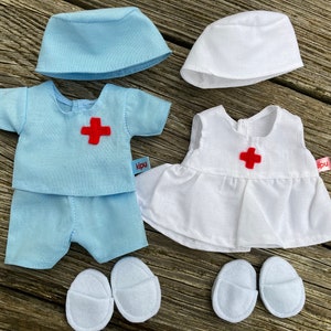 Könnte beinhalten: Zwei Puppenoutfits zum Rollenspiel. Ein Outfit ist blau mit einem roten Kreuz und das andere ist weiß mit einem roten Kreuz. Beide Outfits beinhalten einen Hut und Schuhe.